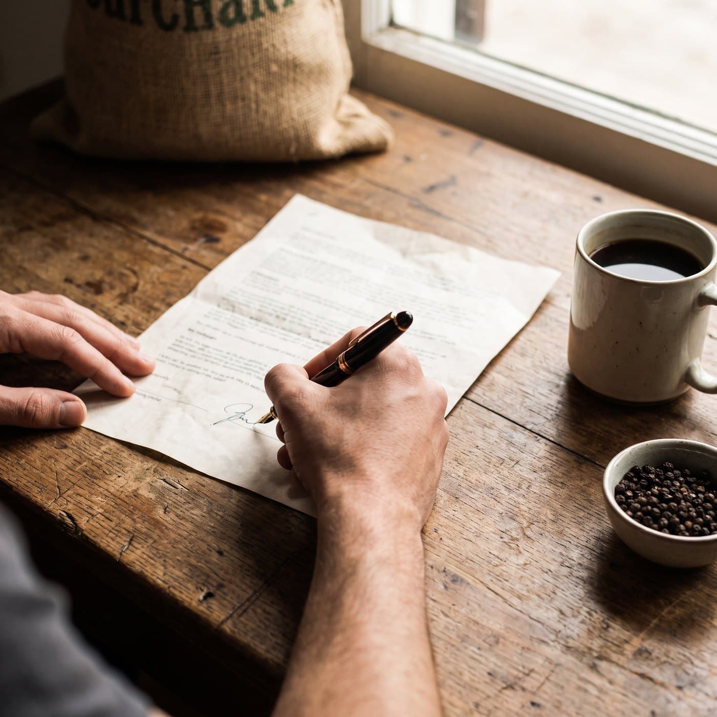 An export contract being signed at a desk, with black tea and peppercorns alongside
